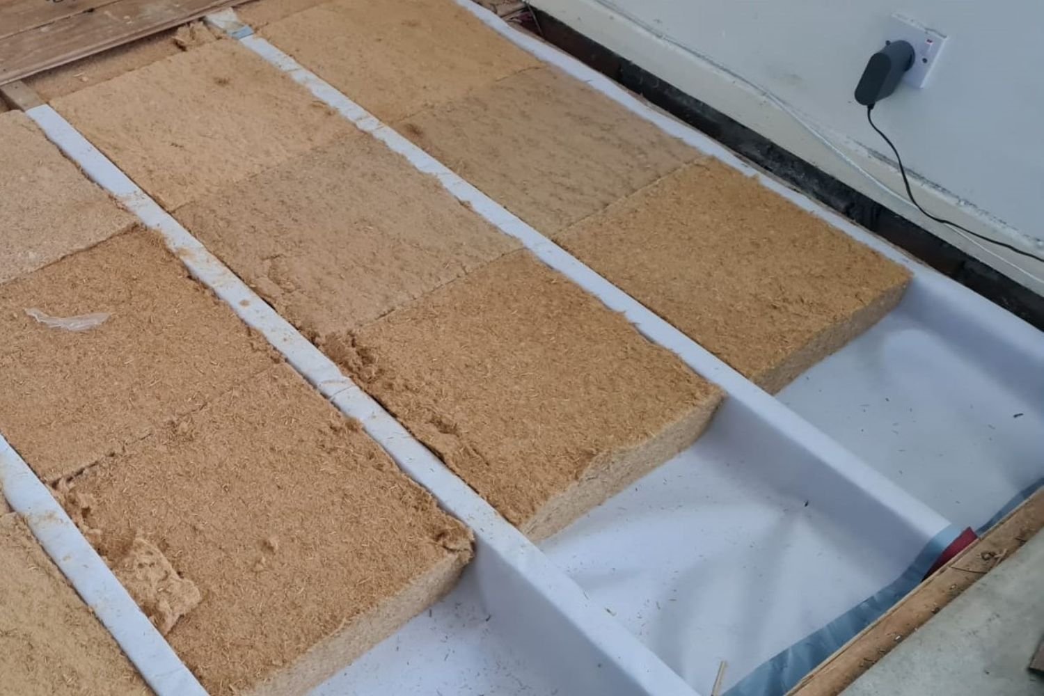 A construction site showing the floor being readied for insulation, with equipment and materials in place for installation.