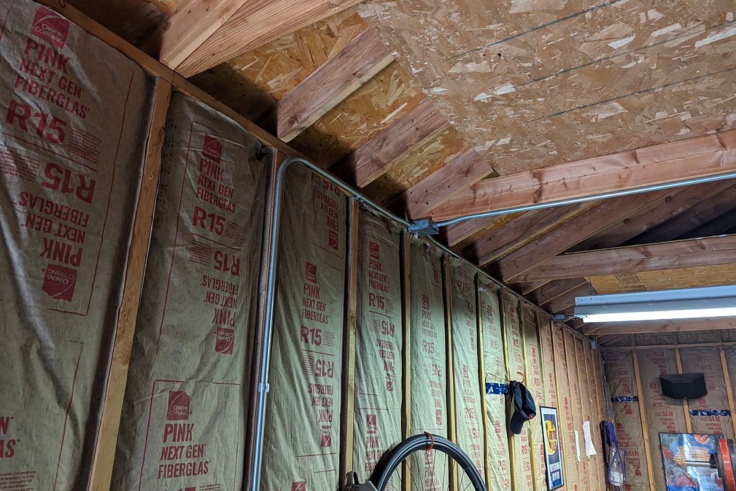A garage featuring a large wooden wall with visible insulation, showcasing a functional and organized space.