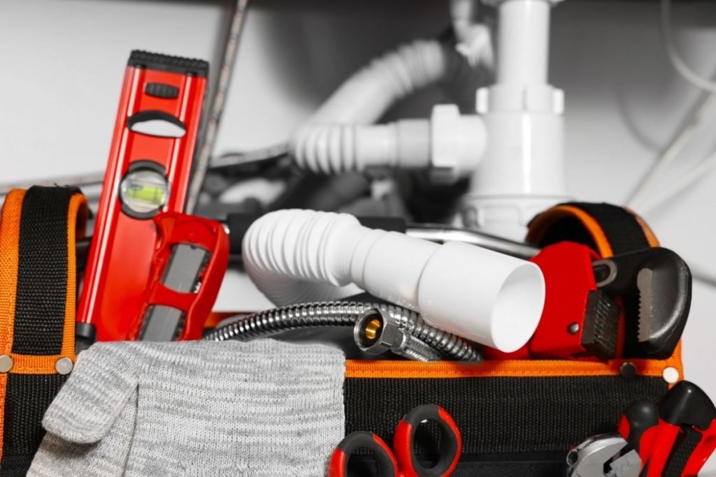 A tool bag filled with various plumbing supplies, including wrenches, pipes, and fittings, arranged neatly inside.